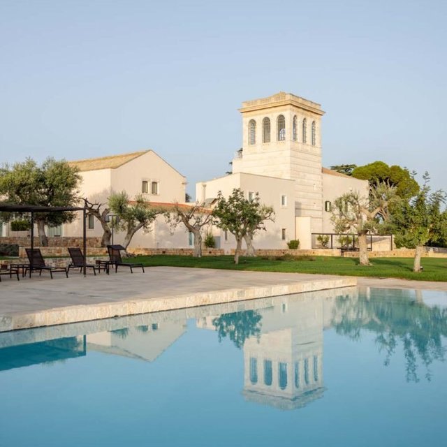 Villa Torre Bianca's tower reflected in the pool among olive trees