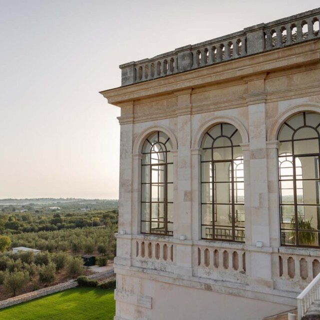 Arched windows and stone balustrade of Villa Torre Bianca above the olive groves